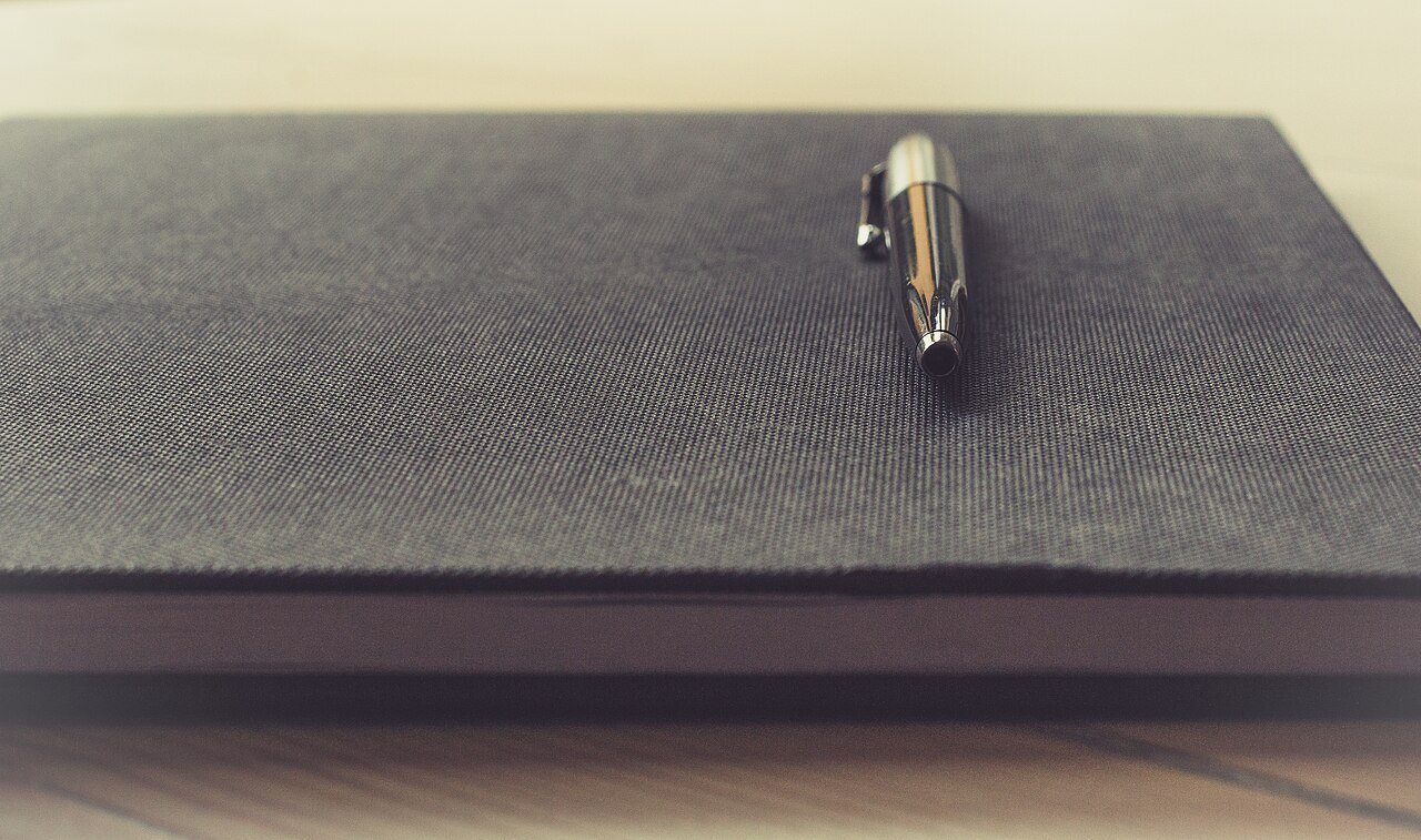 A notebook and pen, shown as a travel-writing illustration.